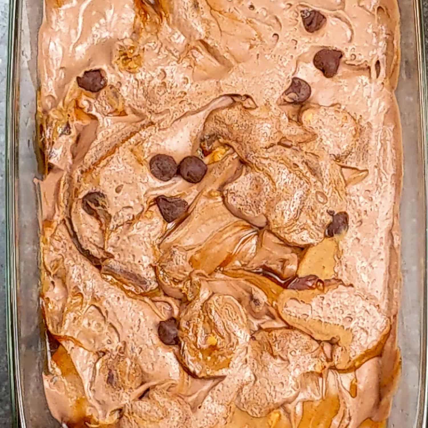 Delicious chocolate ice cream with dark chocolate chips in a clear glass dish.